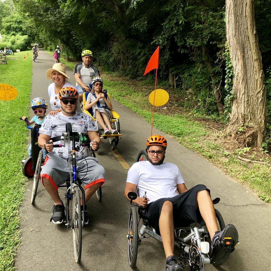 A large group rides various adaptive cycles on a bike path.