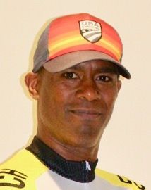 A man wearing a hat and bike shirt, James Fitzgerald, smiles at the camera.