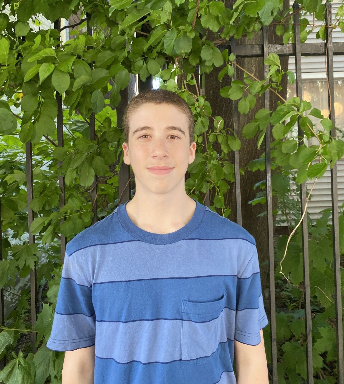 Image shows a teenager wearing a blue striped shirt smiling at the camera