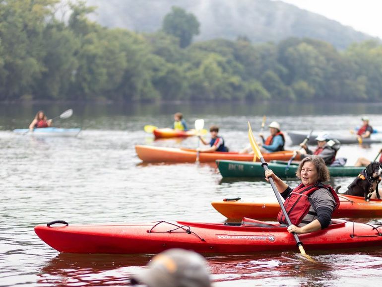 A group of people including State Senator Jo Comerford are paddling kayaks on a river.