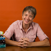 Riley Caldwell O'Keefe is sitting at a table with her hands folded and smiling.