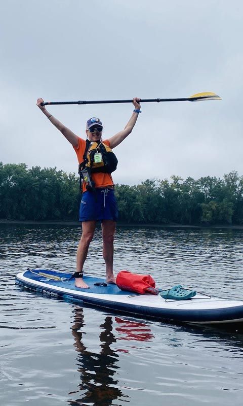 A woman is standing on a paddle board in the water holding a paddle.