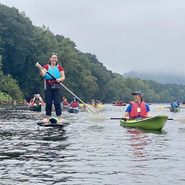 State Representative Lindsay Sabadosa is standing on a paddle board in the middle of a river.