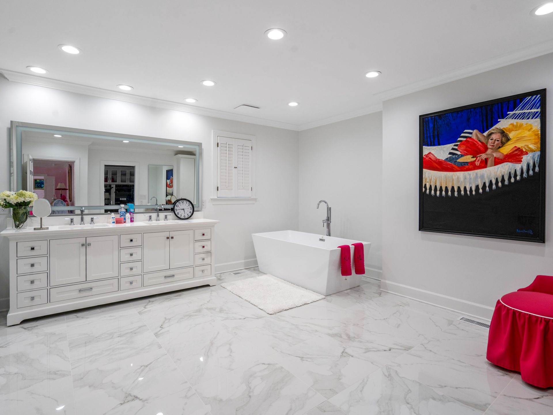 Bright white bathroom with marble floors, a freestanding tub, and a large piece of art.