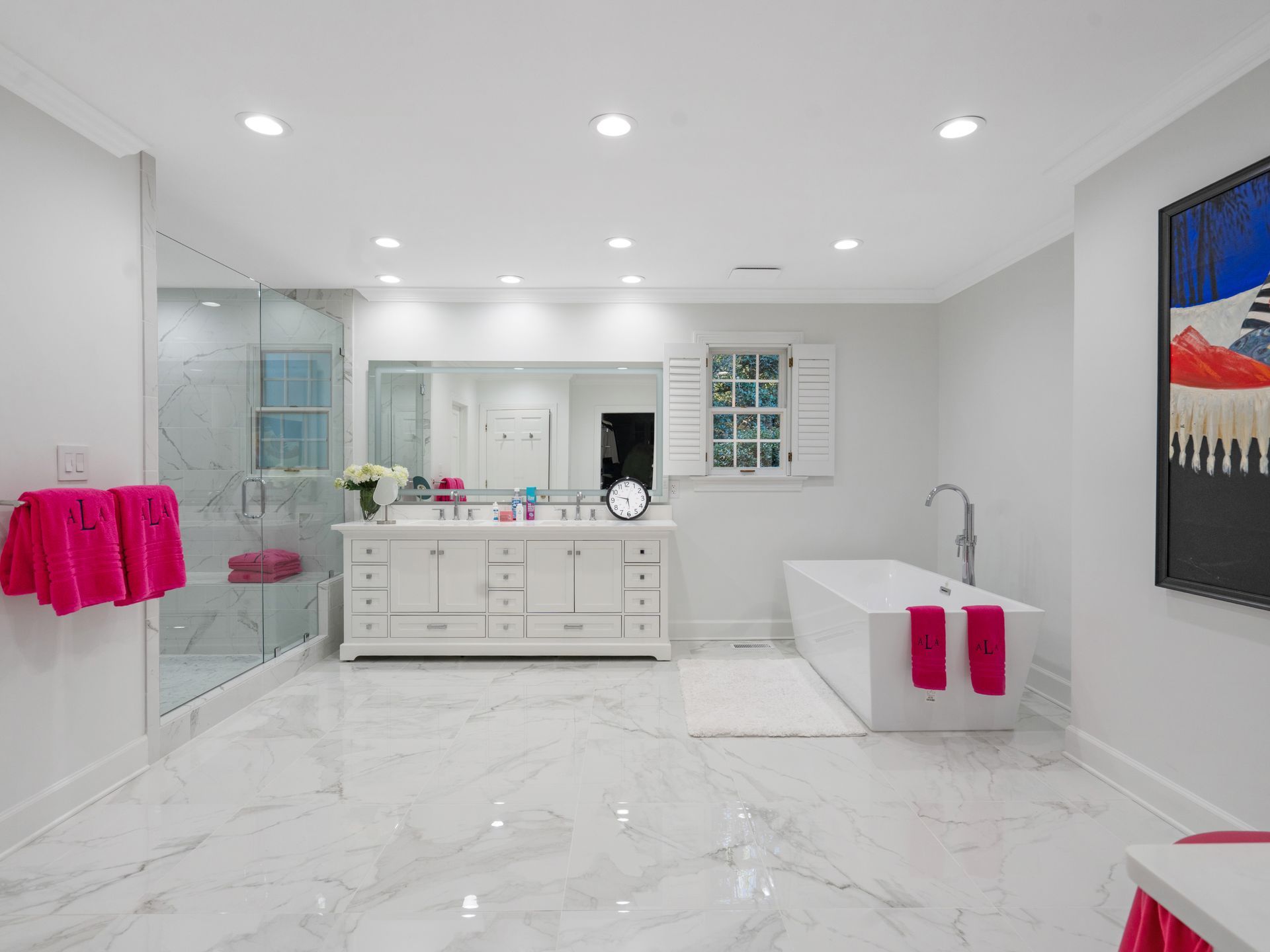 Bright white modern bathroom with marble floors, a soaking tub, and pink towels.