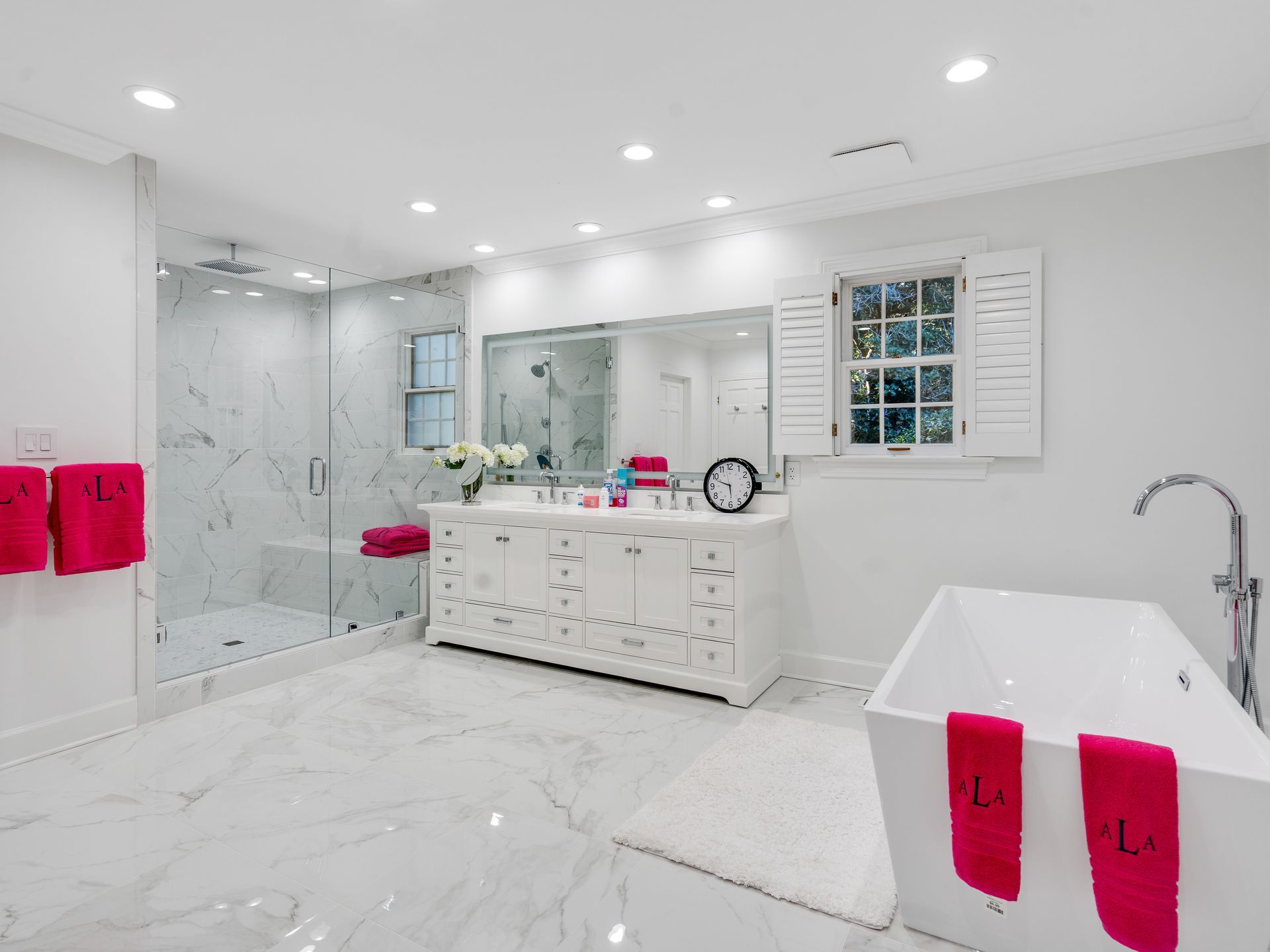 Bright white bathroom with marble floors, shower, double vanity, and freestanding tub.