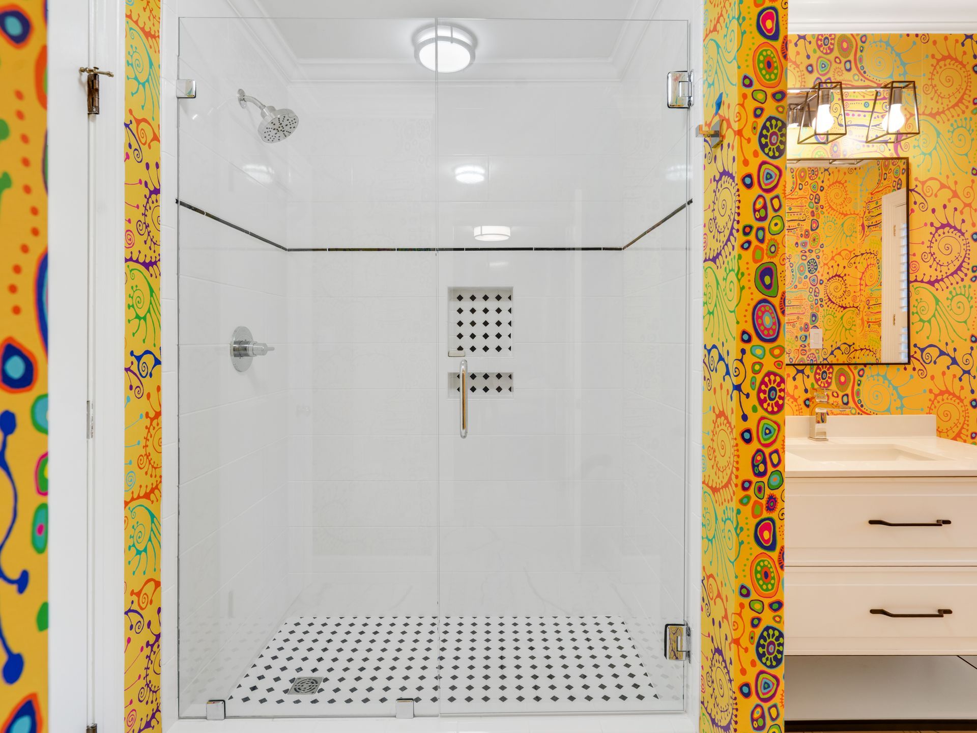 Bathroom with a glass-enclosed shower, white tile, and patterned yellow wallpaper.
