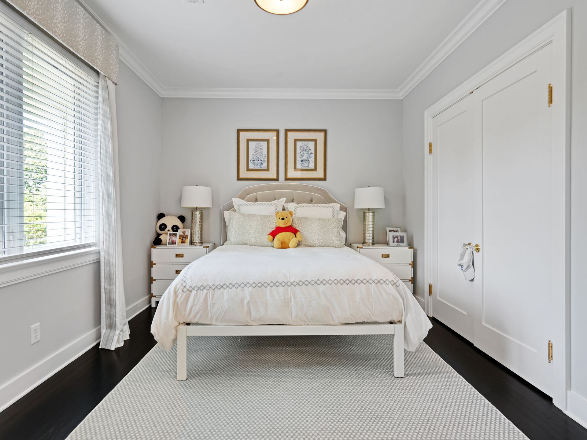 Cozy white bedroom with bed, nightstands, panda, and Winnie the Pooh. Light walls, dark floor, and bright window.