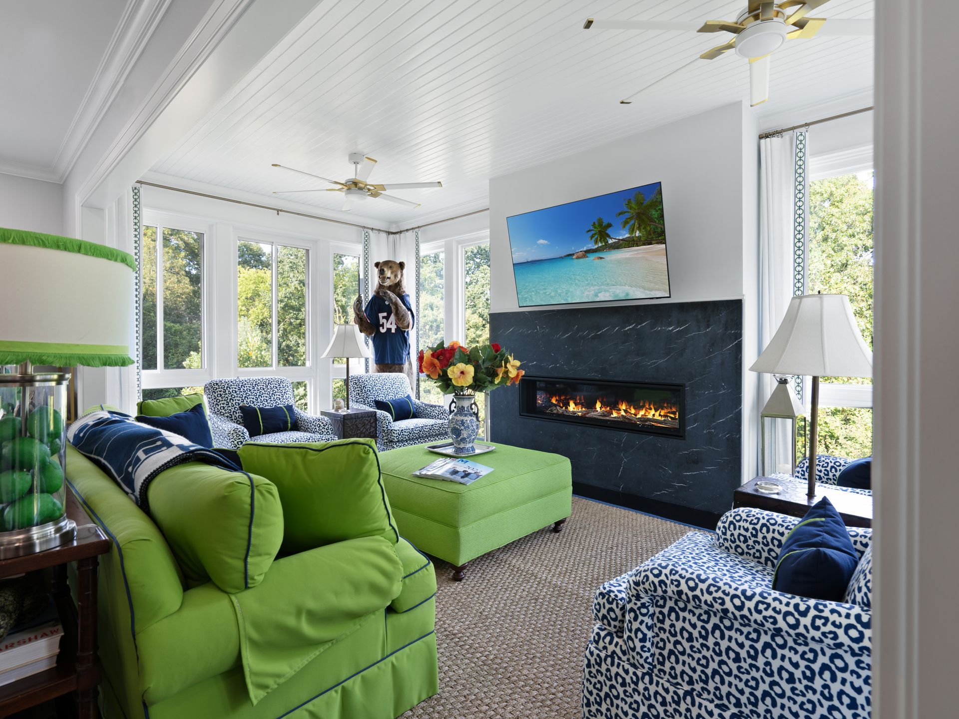 Bright living room with lime green furniture, navy and white patterned armchairs, fireplace, and large windows.