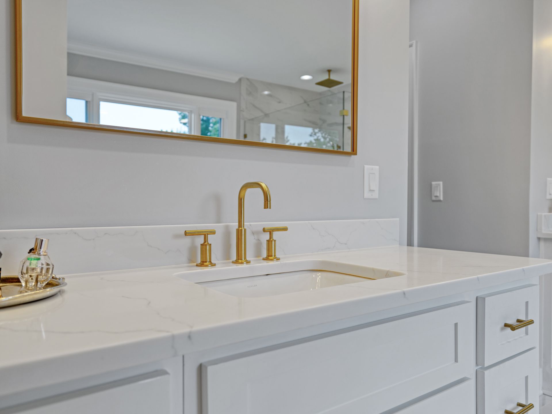 White bathroom vanity with gold faucet, mirror, and hardware.