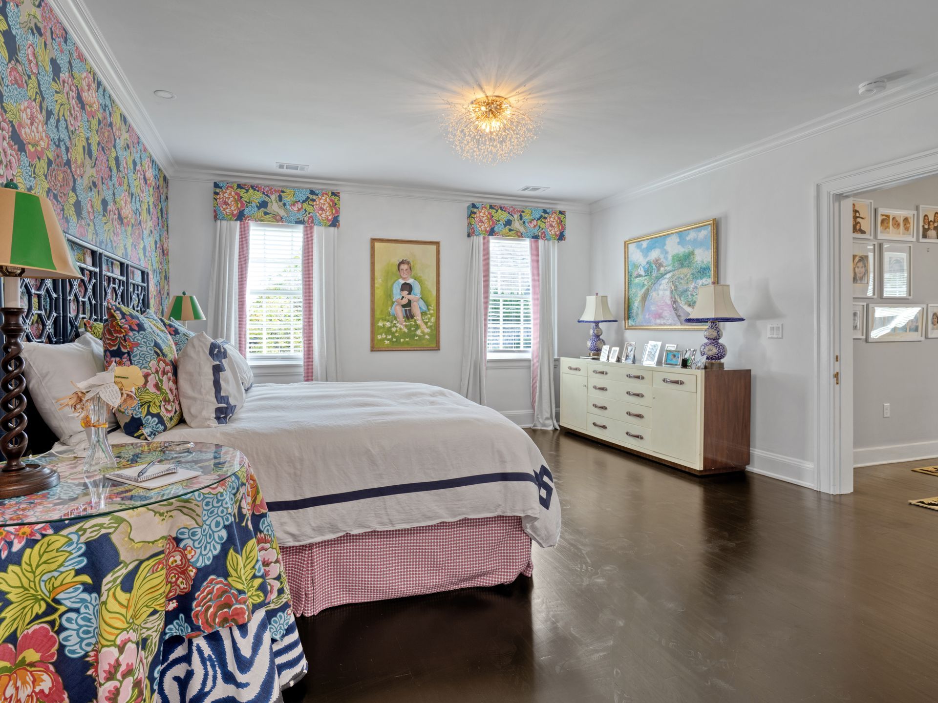 Bedroom with floral wallpaper, bed, dresser, and dark wood floor.