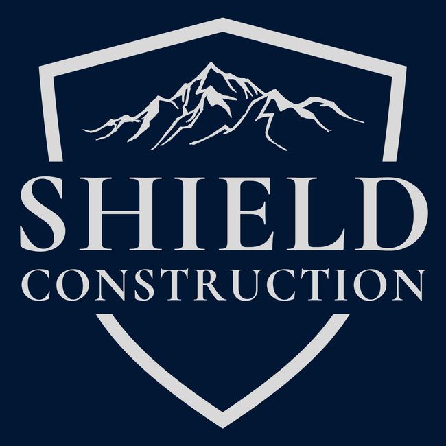 Logo for Shield Construction with a mountain silhouette inside a shield on a navy blue background.