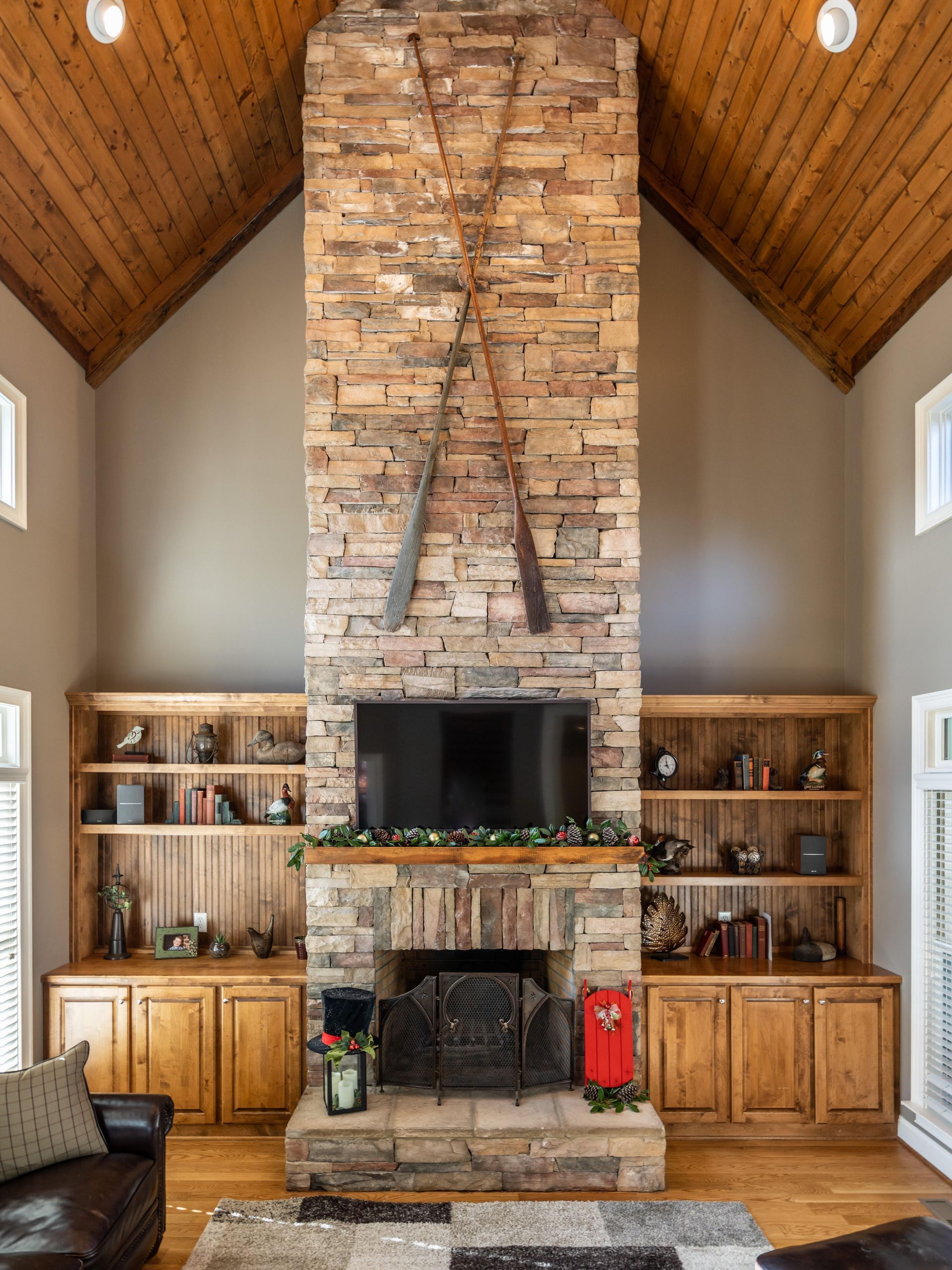 A raised stone patio with a black metal railing next to a white house with a ground-level window and a grassy slope.