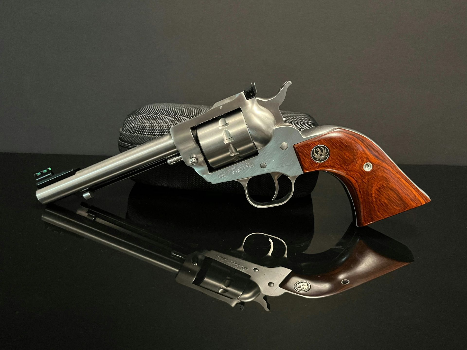 A stainless steel revolver with a wooden grip is sitting on a table.