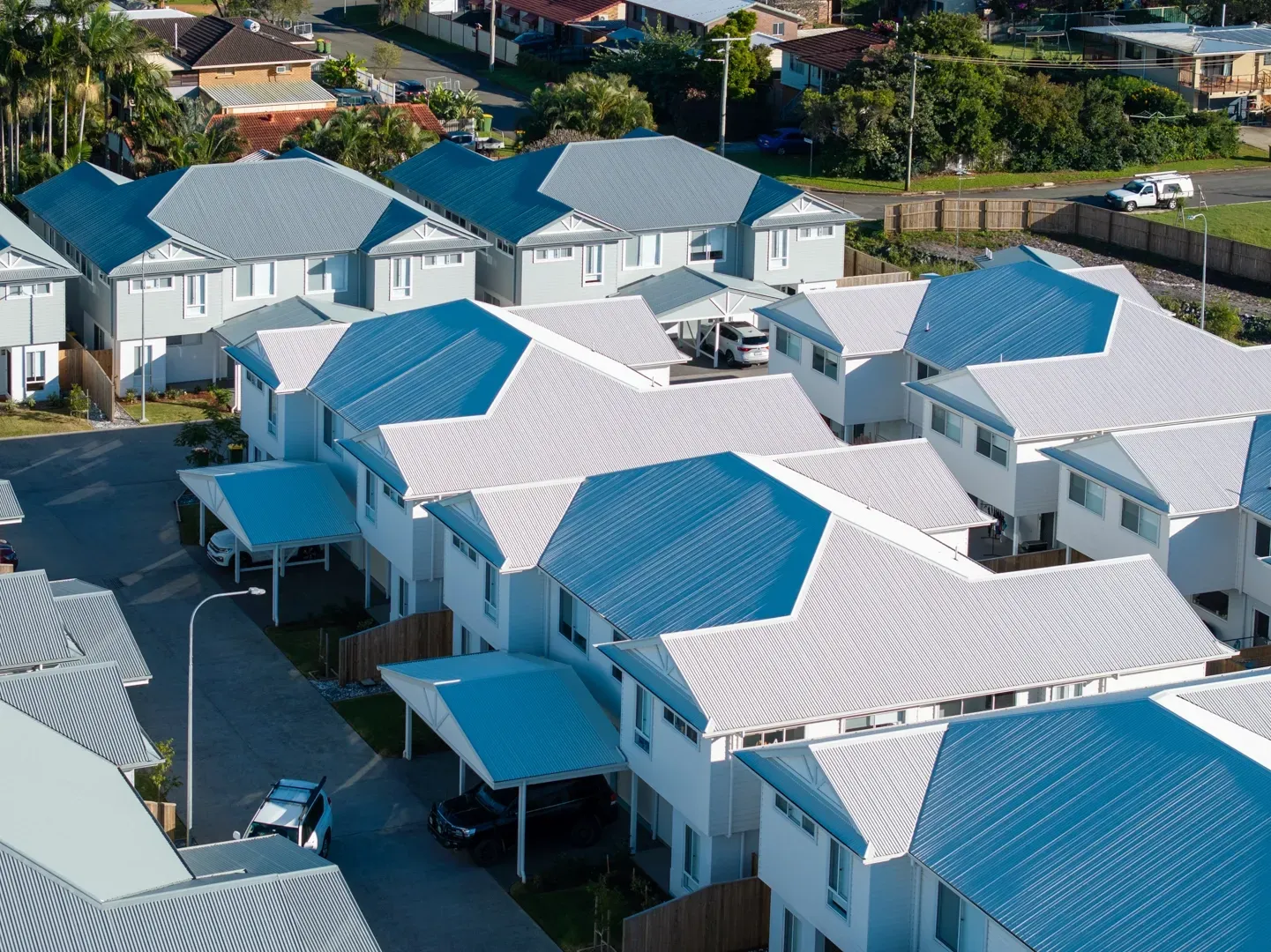 Aerial view of townhouses with light blue roofs and white walls, clustered together. — Smart Metal Roofing in Coomera, QLD