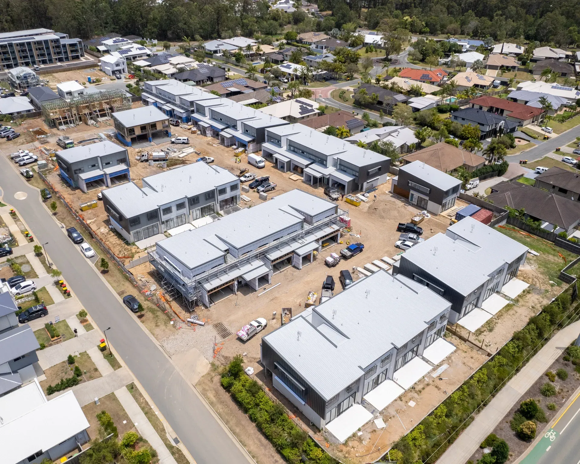 Aerial view of a suburban construction site with multiple newly built gray townhouses. — Smart Metal Roofing in Coomera, QLD