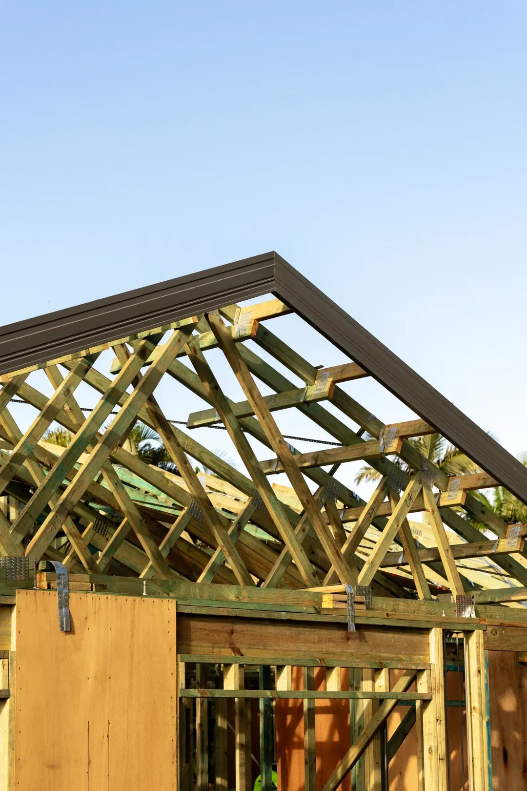 Wooden roof trusses under construction; blue sky background. — Smart Metal Roofing in Coomera, QLD