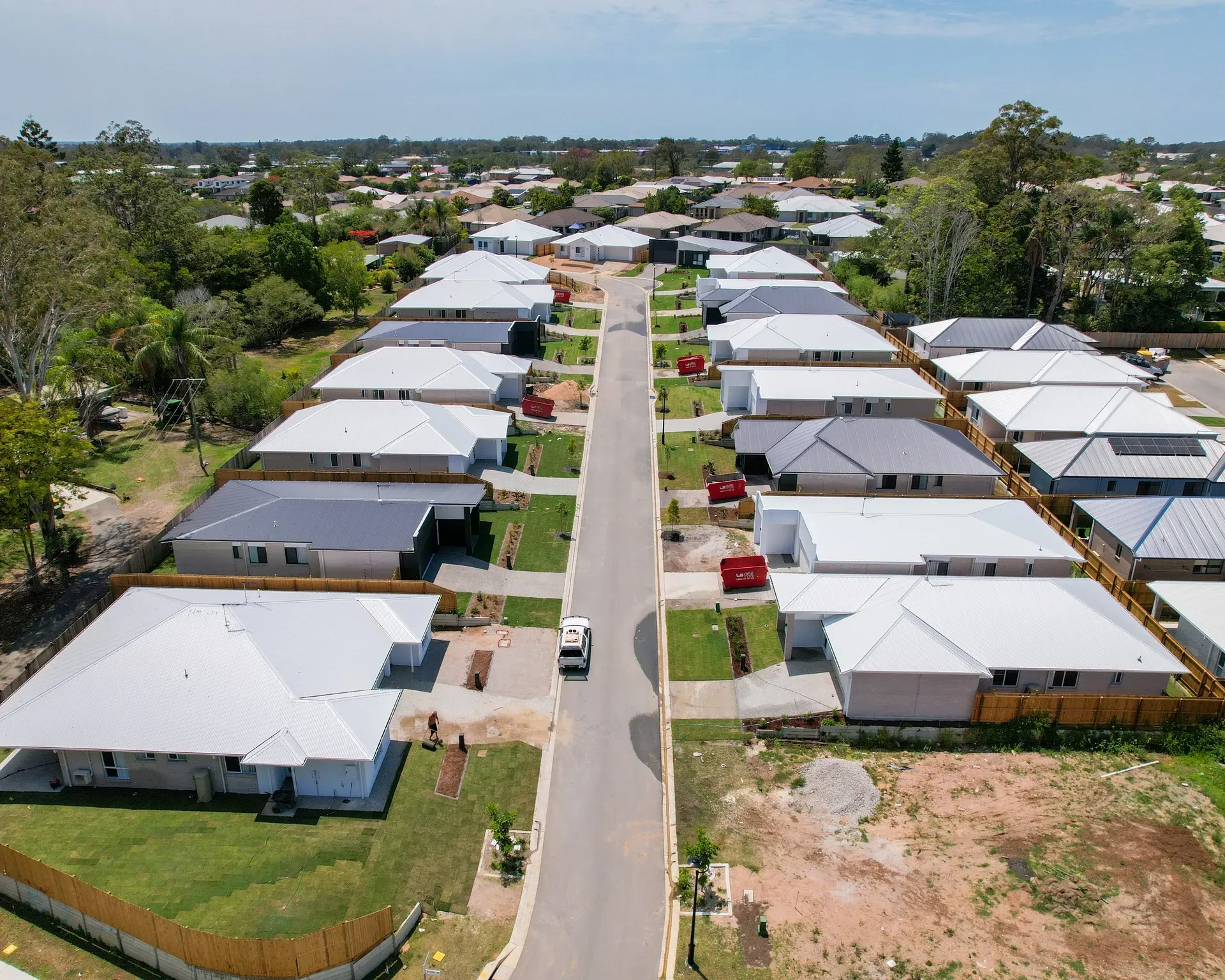 Aerial view of a suburban street lined with newly built houses, under a blue sky — Smart Metal Roofing in Coomera, QLD