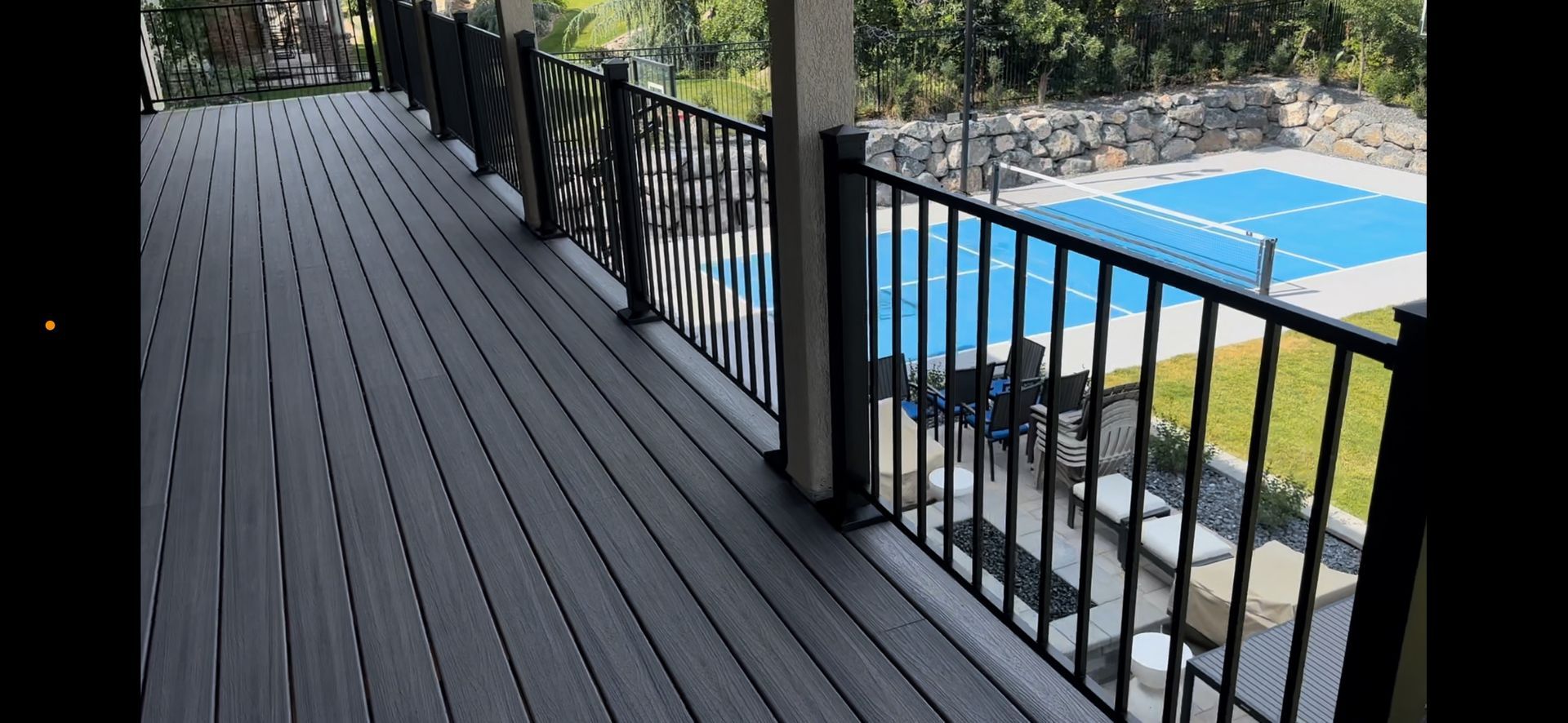 A large deck with a black railing overlooking a swimming pool.