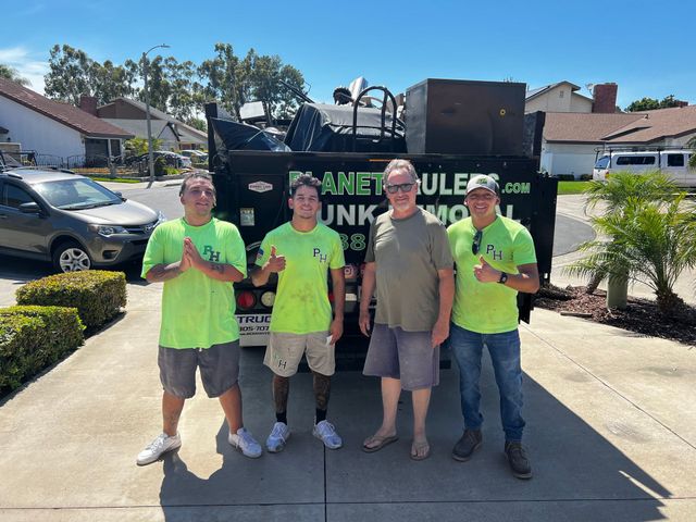 A group of men standing in front of a dumpster that says junk removal
