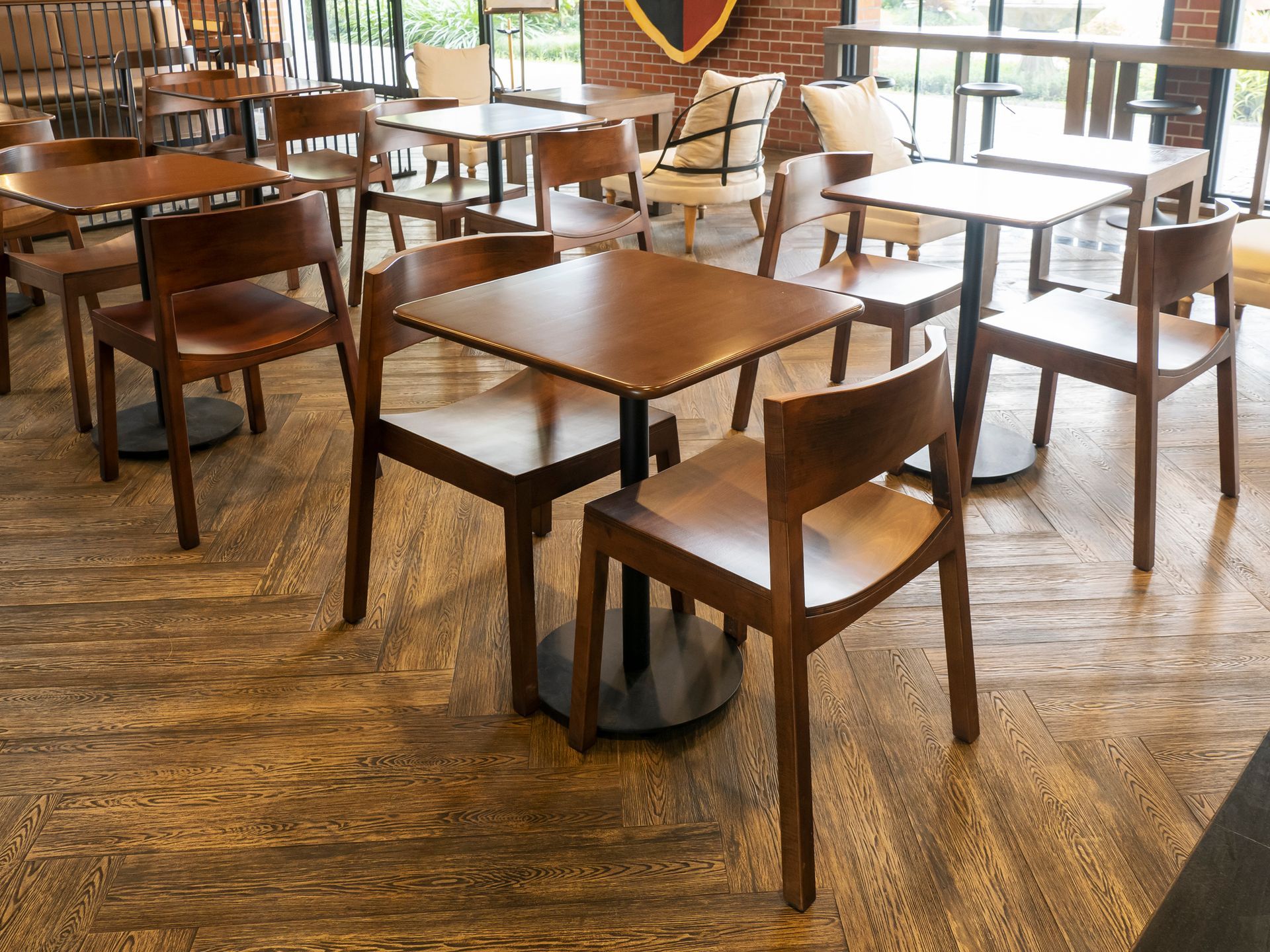 Bright interior with large windows overlooking an outdoor campus, reflecting on a shiny floor.