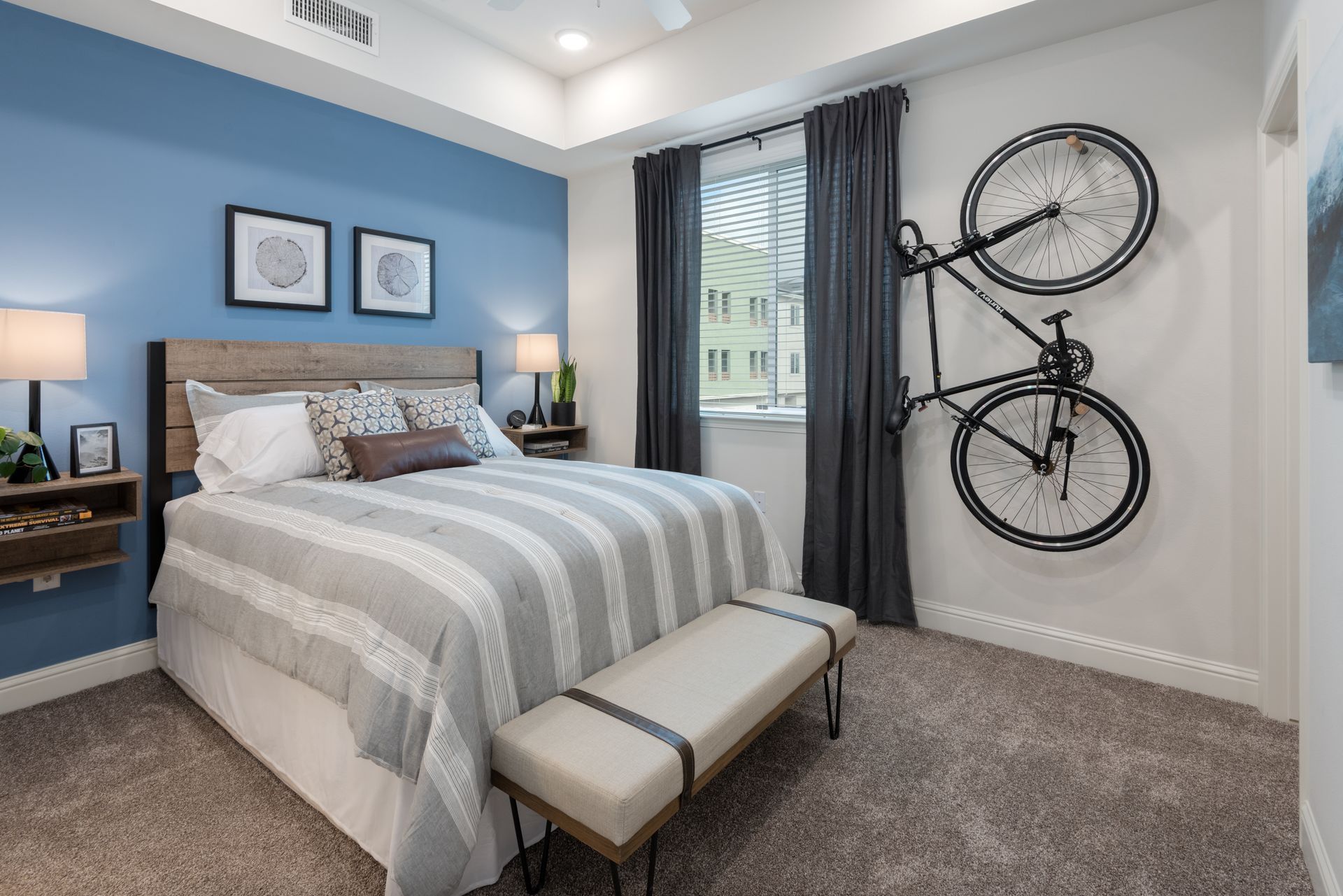 Bedroom with a bed, blue wall, bike on wall, and a window.