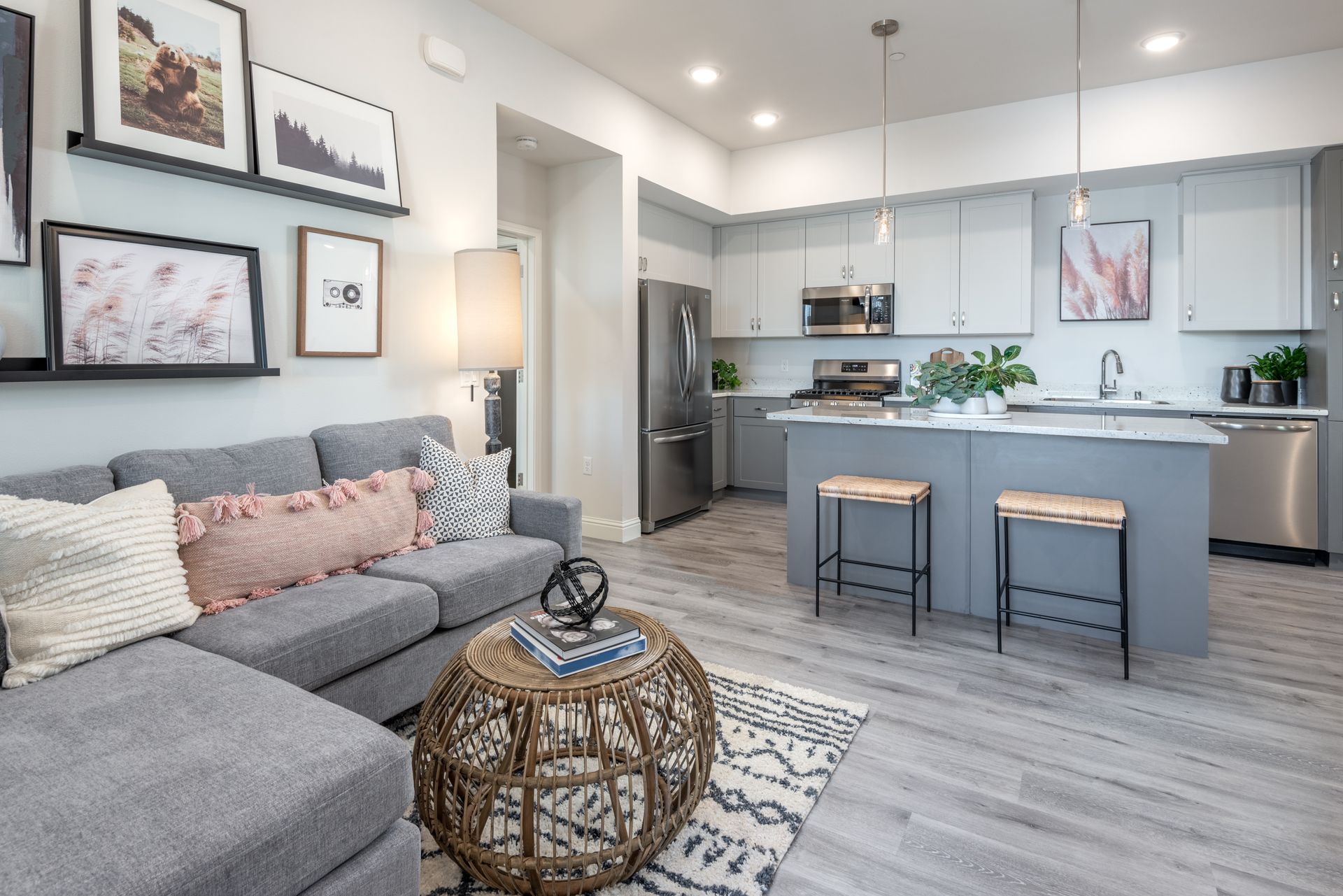 Modern living room with an open-plan kitchen featuring a gray sectional sofa, gray cabinets, and a central island.