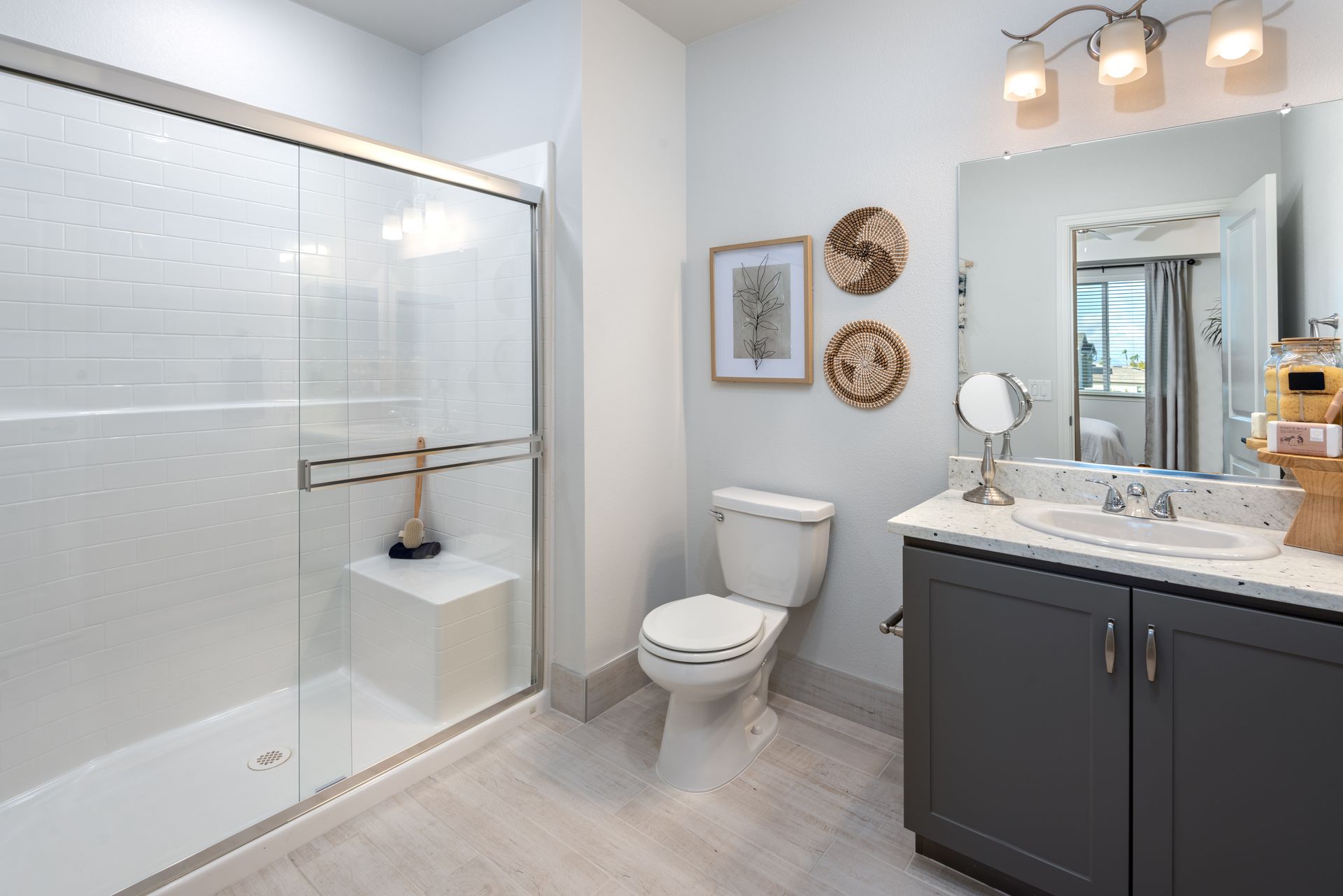 Bathroom with a glass shower, toilet, gray vanity, and decorative wall art.