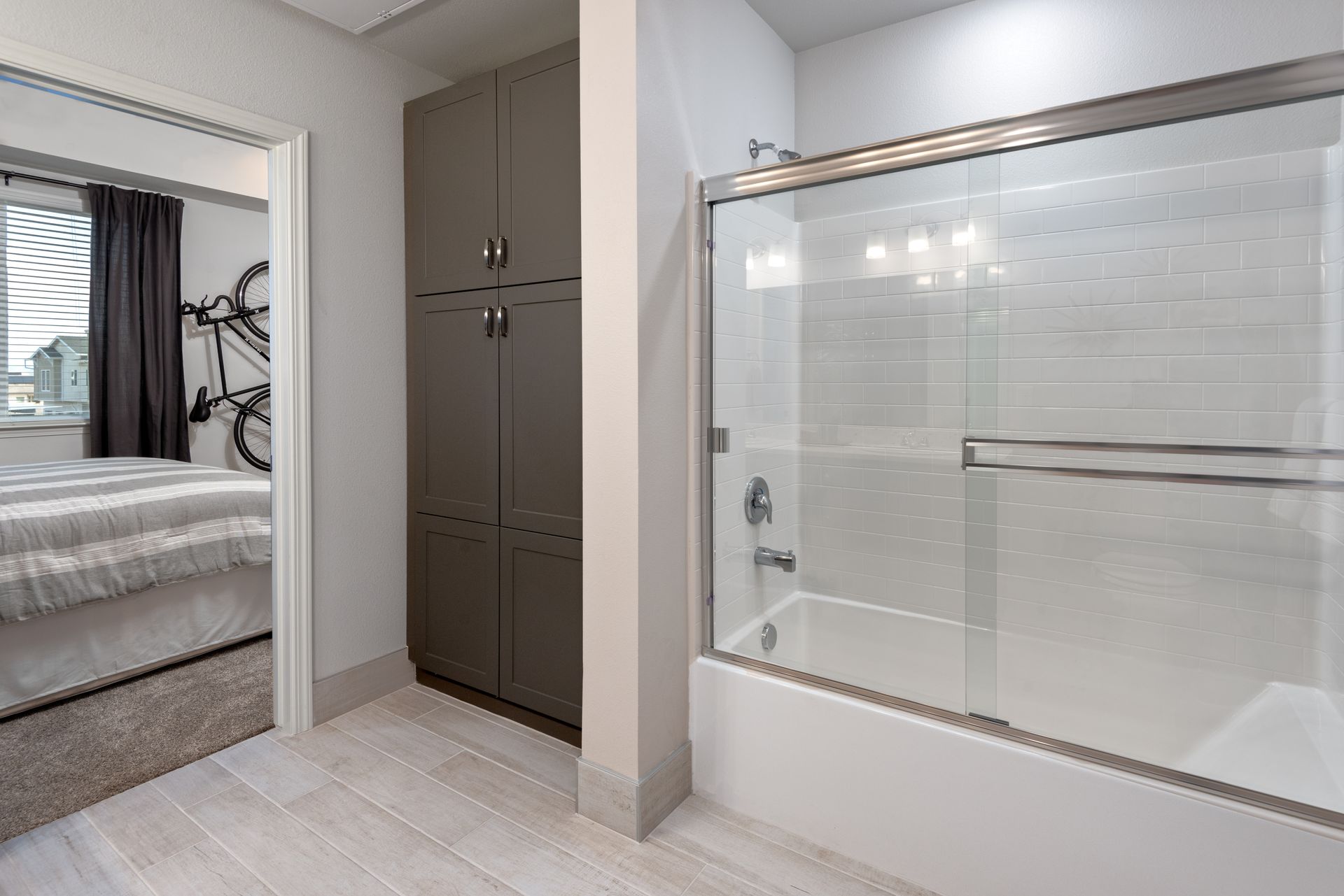 Bathroom with a shower, storage closet, and bedroom doorway visible.
