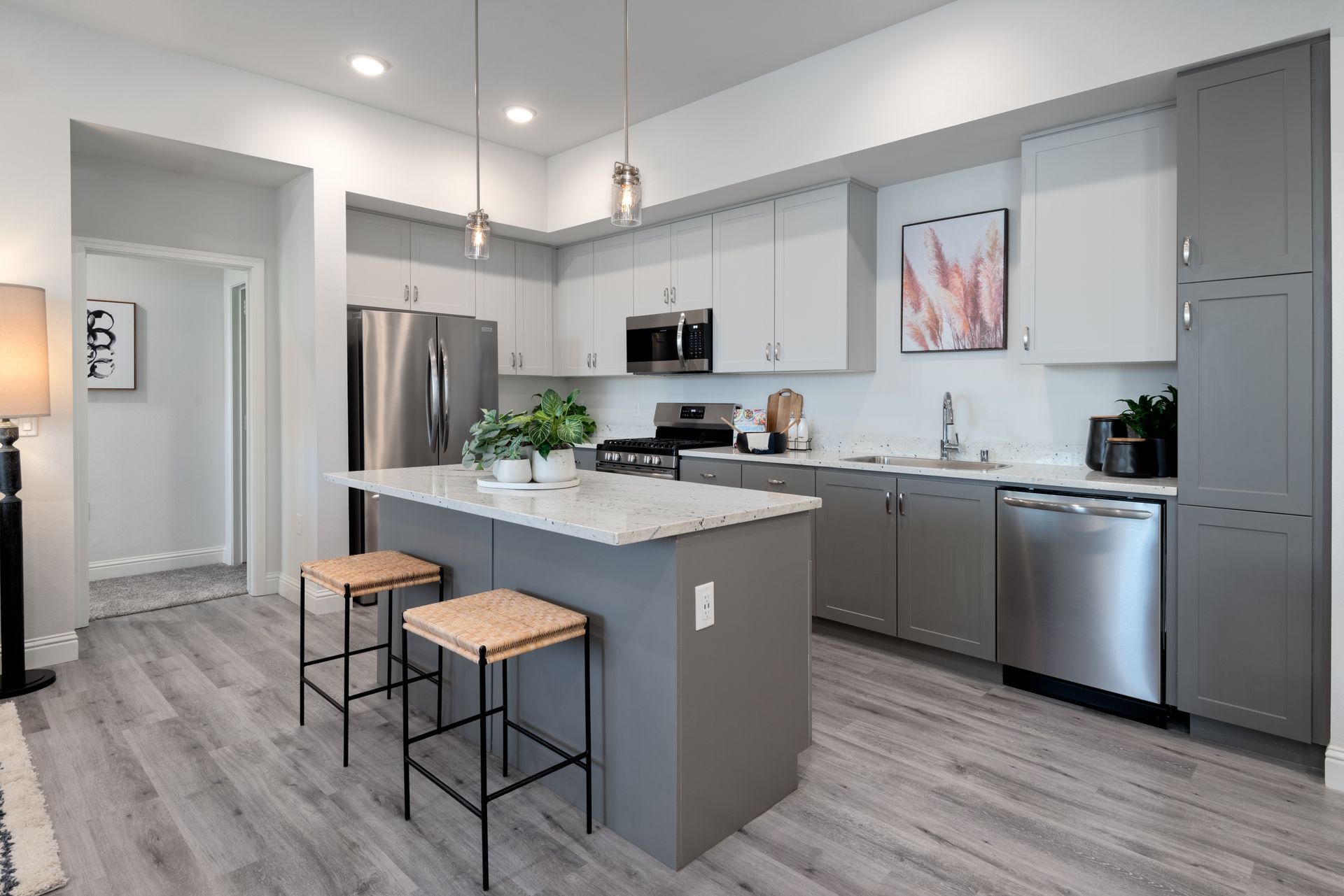 Modern kitchen with gray cabinets, stainless steel appliances, and a white island with two stools.