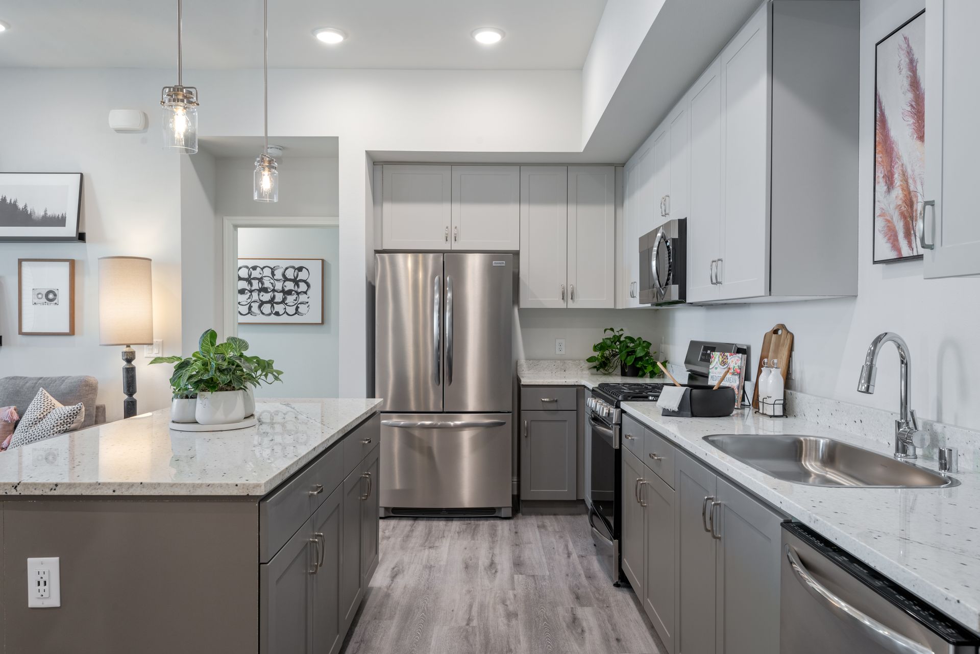 Modern kitchen with gray cabinets, stainless steel appliances, and a large island.
