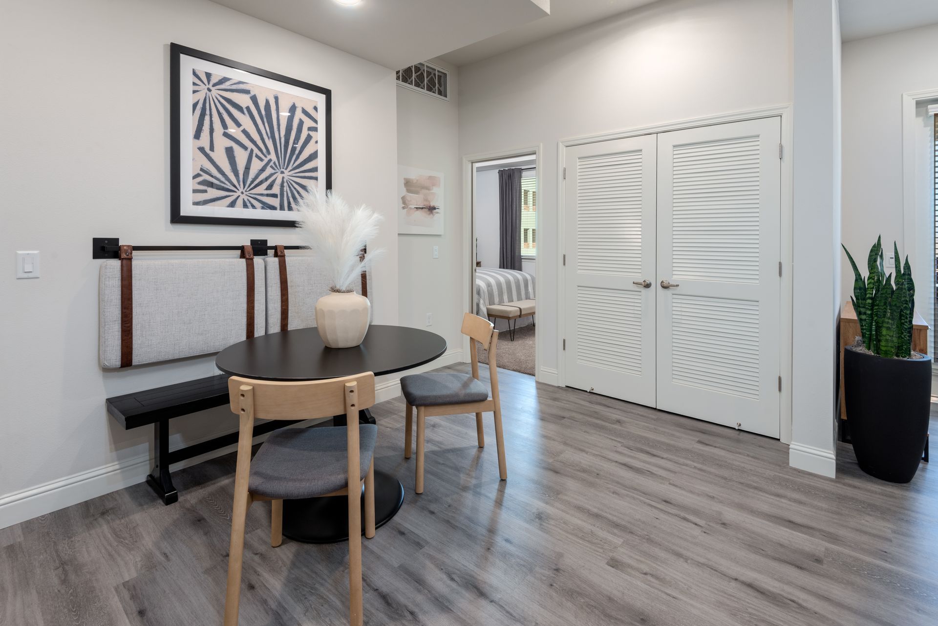 Dining area with a table, bench, chairs, art, and patterned double doors.
