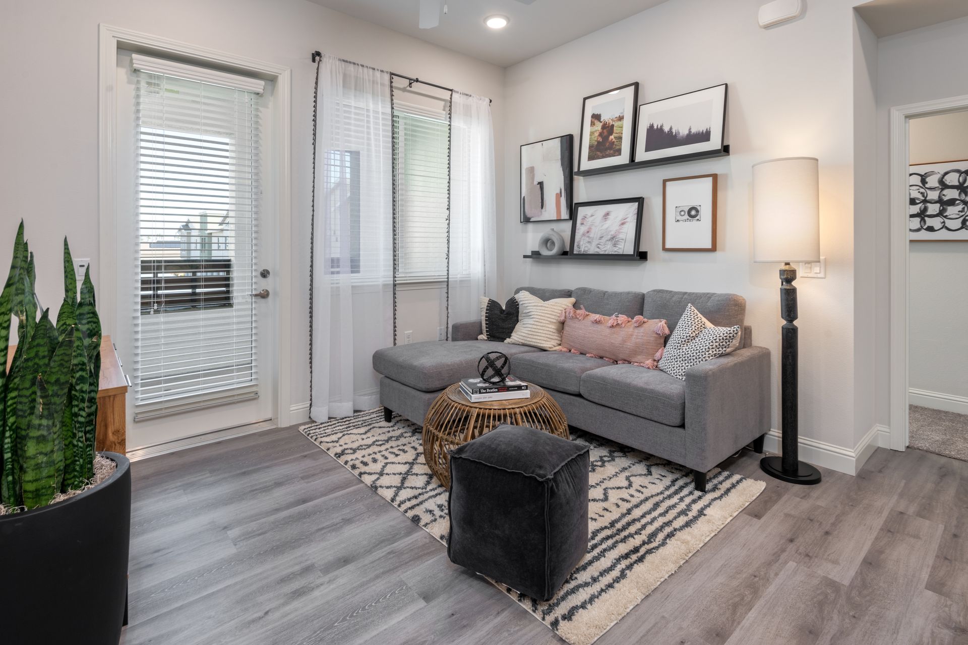 Living room with gray sectional, art, rug, and a door leading to a patio.