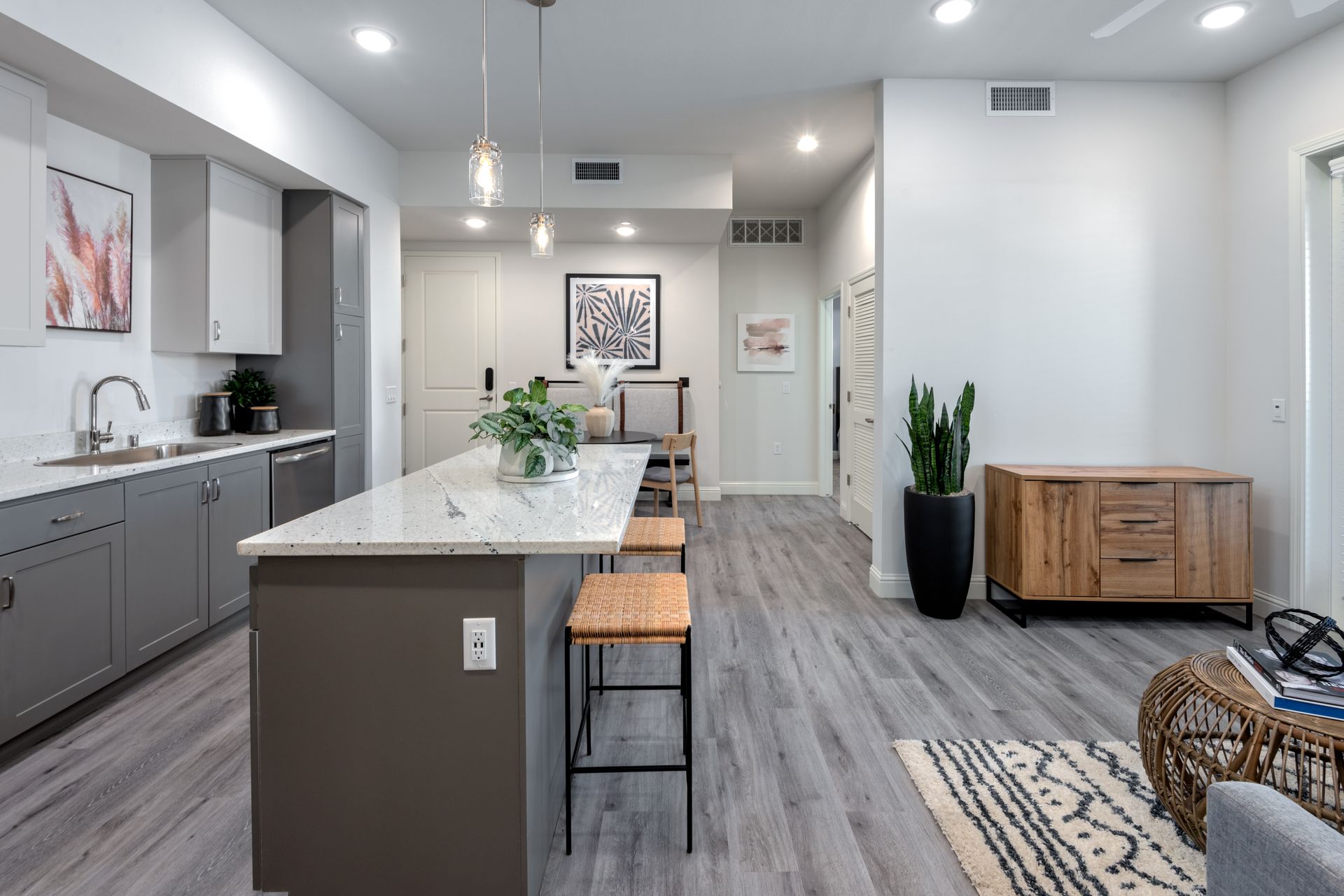 Modern kitchen and living area with gray cabinets, island seating, and wooden furniture.