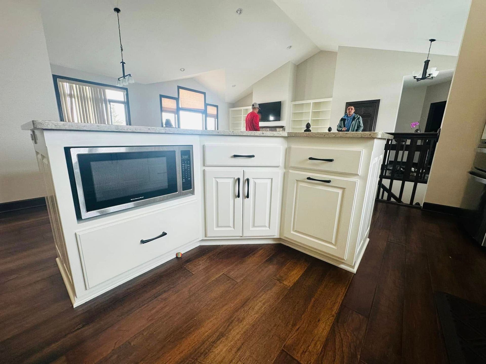 A kitchen with white cabinets and a microwave.