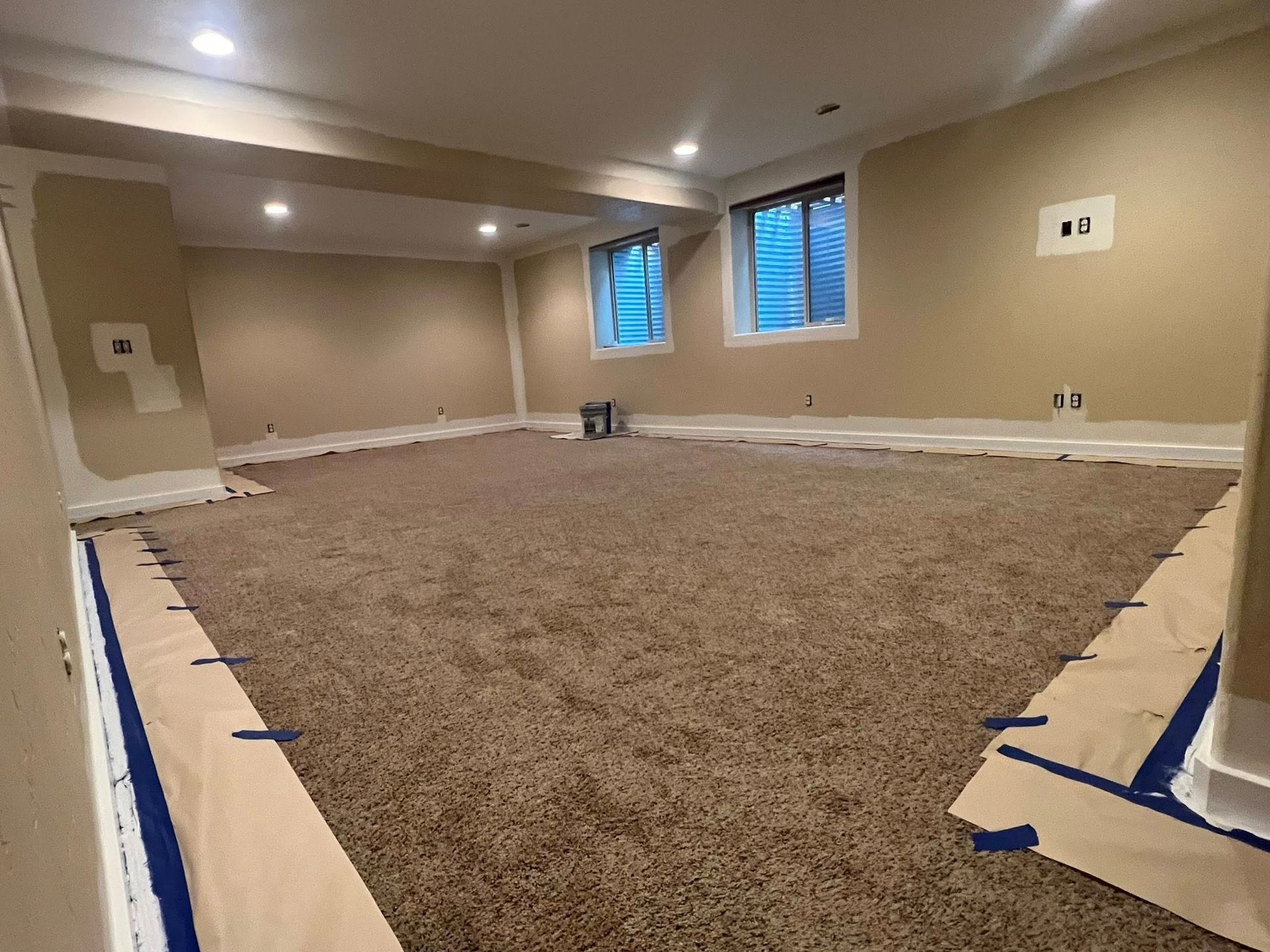 An empty basement with a lot of carpet and windows.