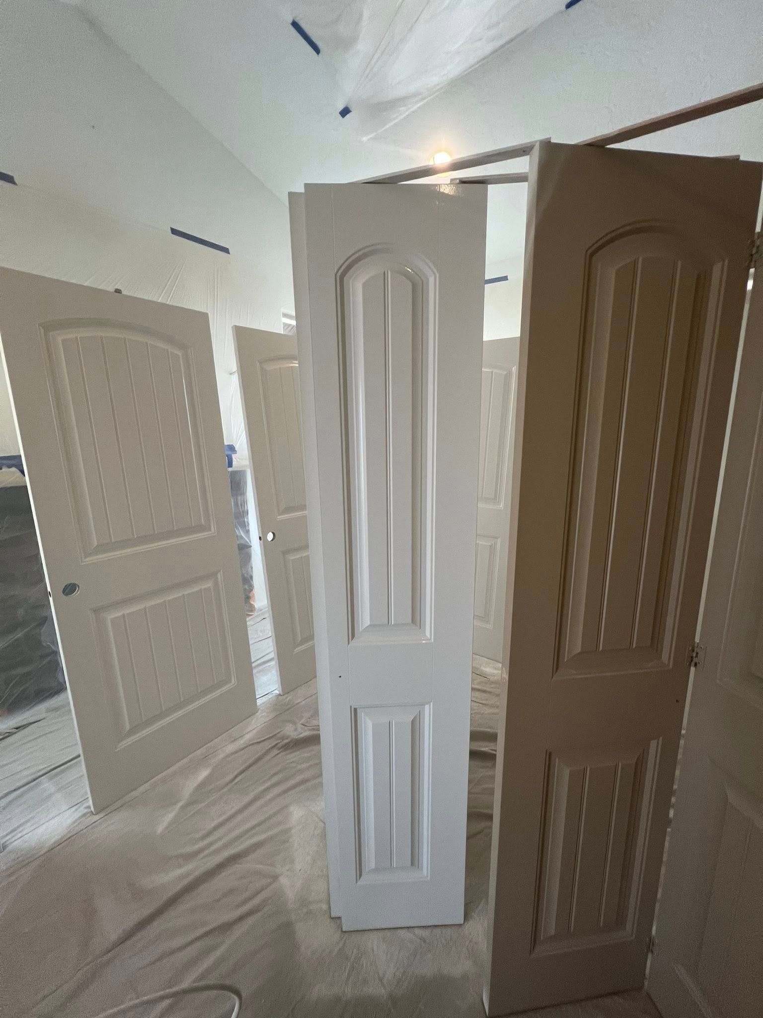 A row of white doors are sitting in a room.