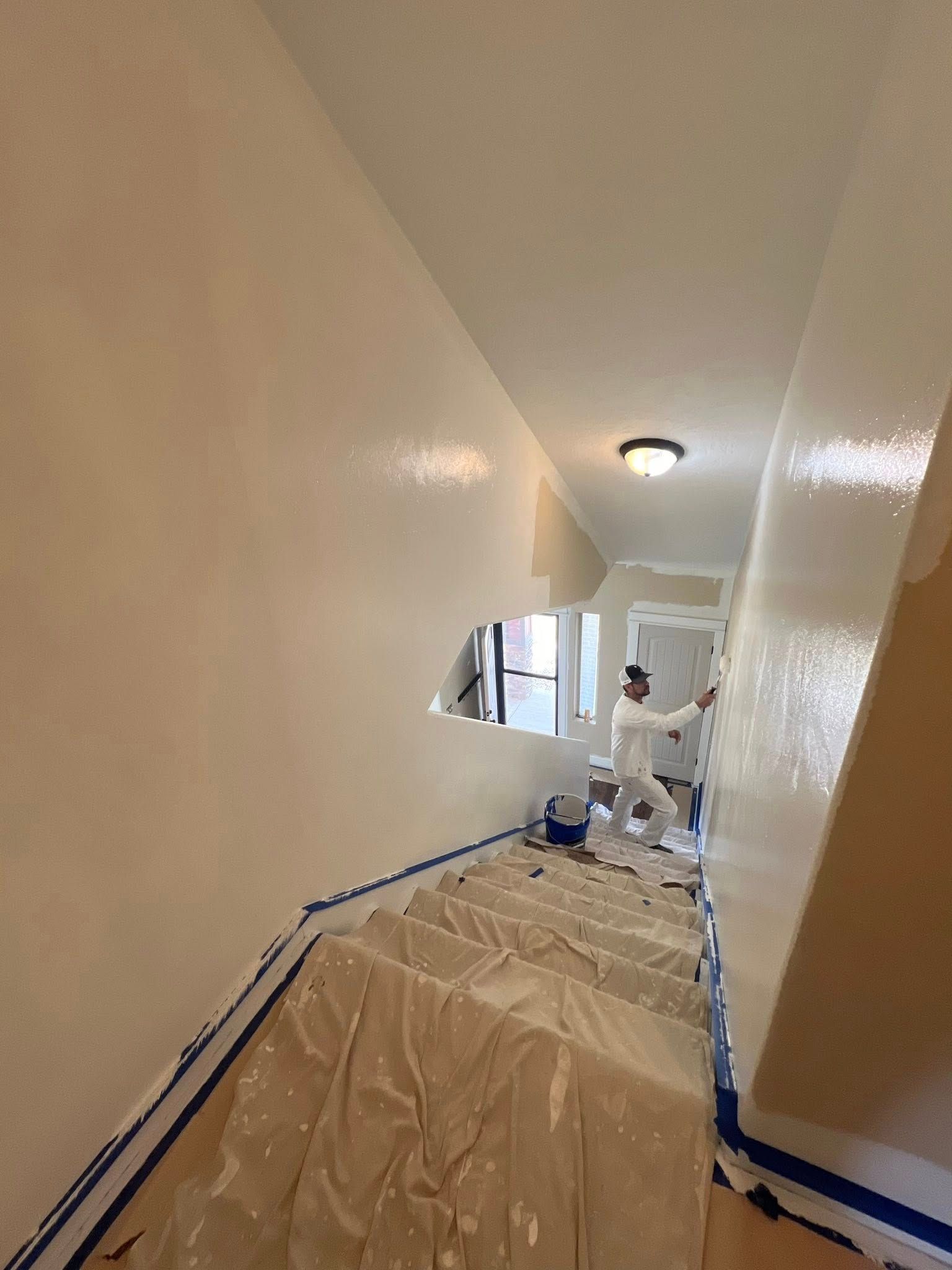 A man is painting a wall in a hallway.