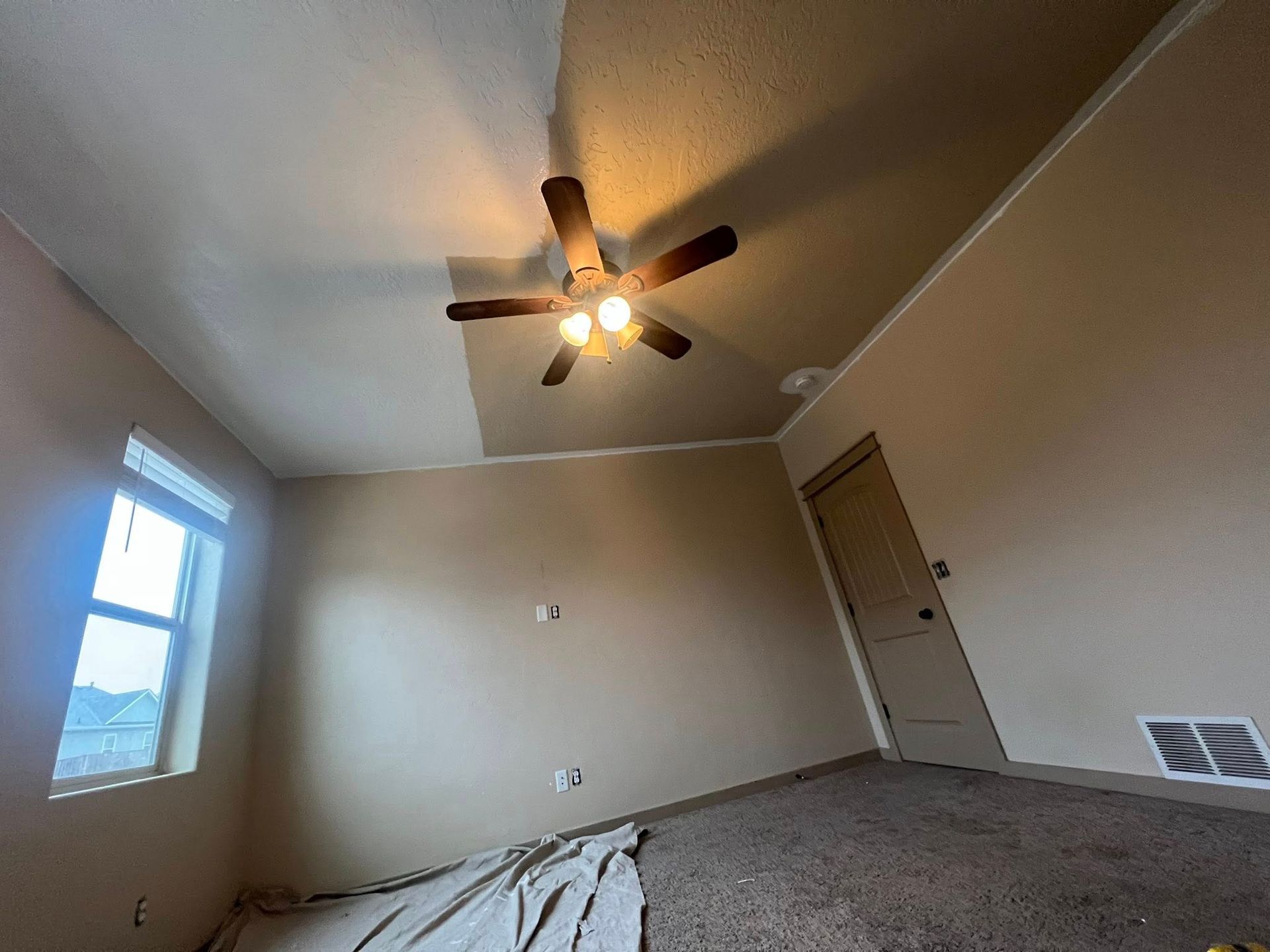 A bedroom with a ceiling fan and a window.
