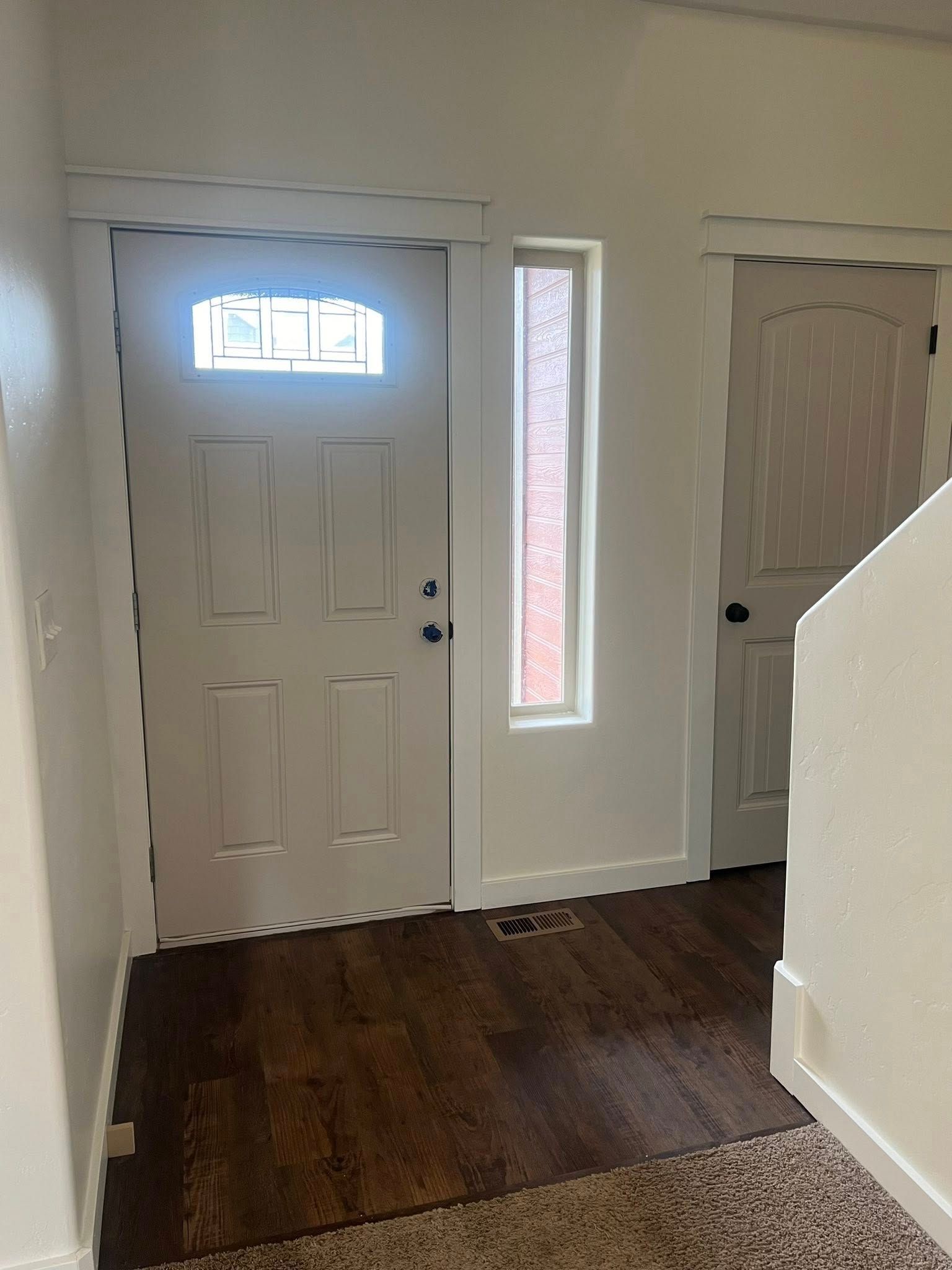 A hallway with a white door and a window.