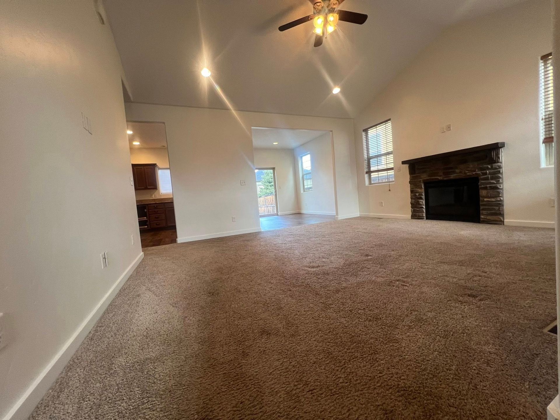 An empty living room with a fireplace and ceiling fan
