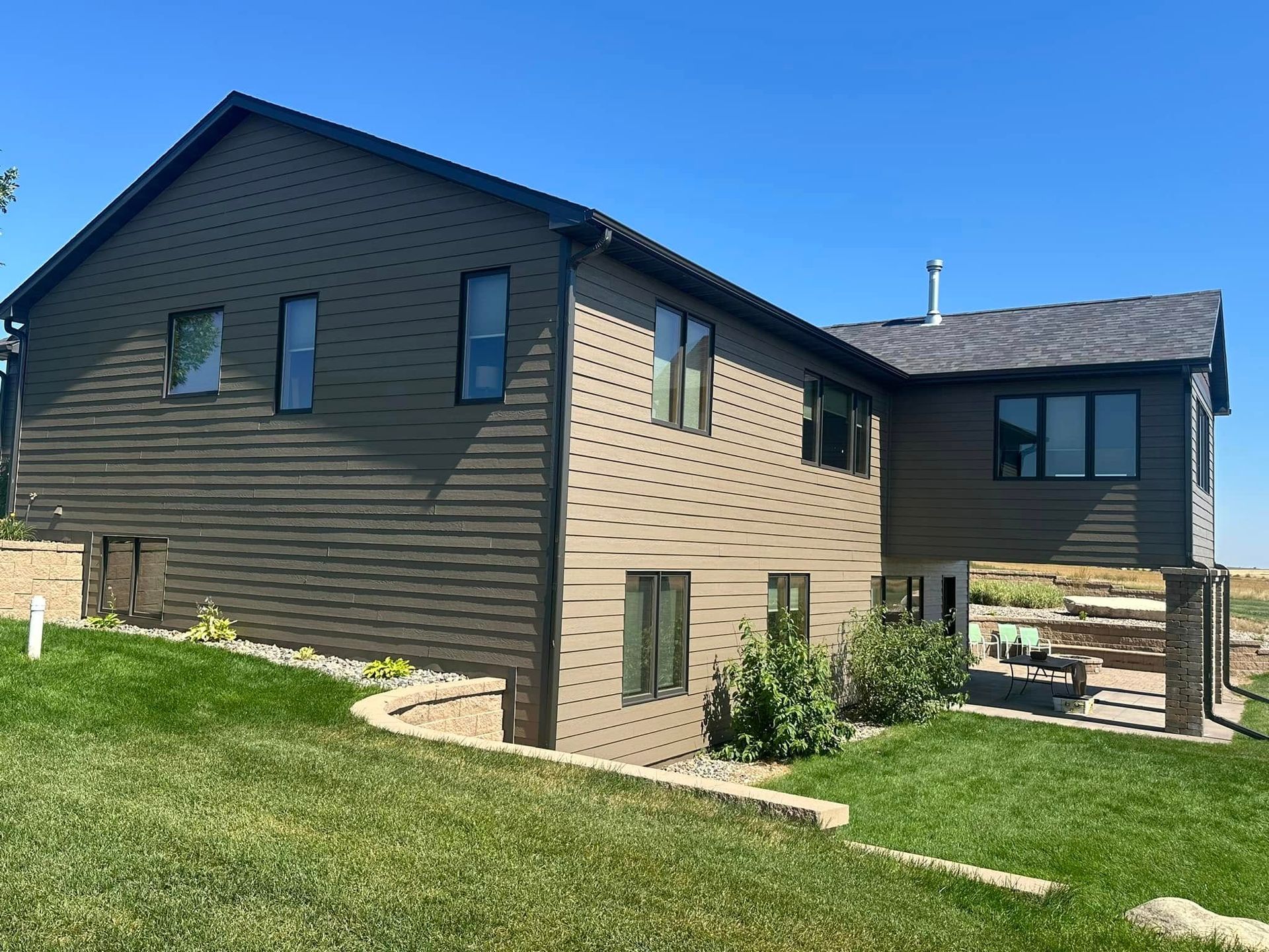 A large house with a lot of windows is sitting on top of a lush green hillside.