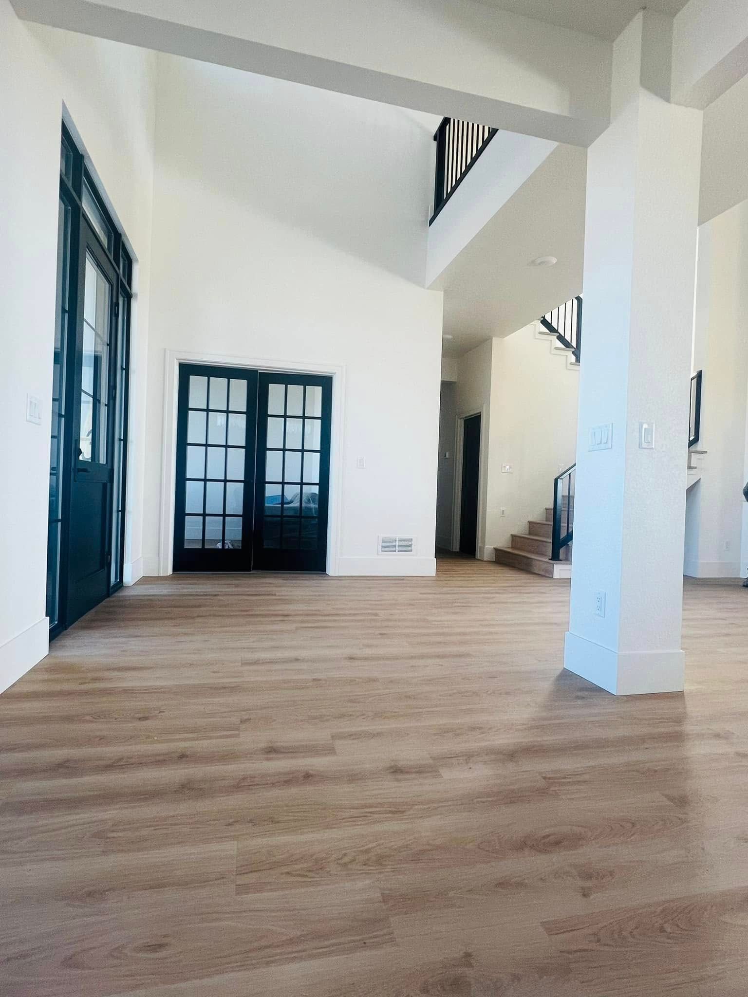 A large empty room with wooden floors and white walls.