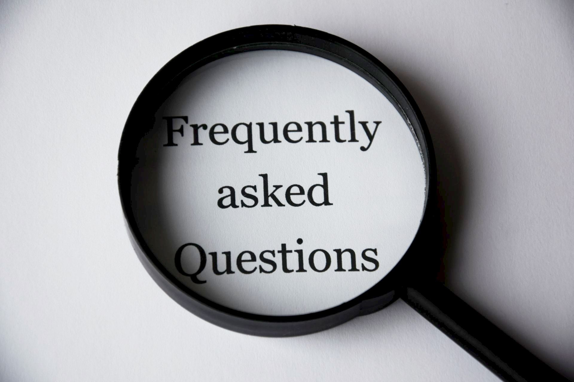 Magnifying glass over the words “Frequently asked Questions” on a white background