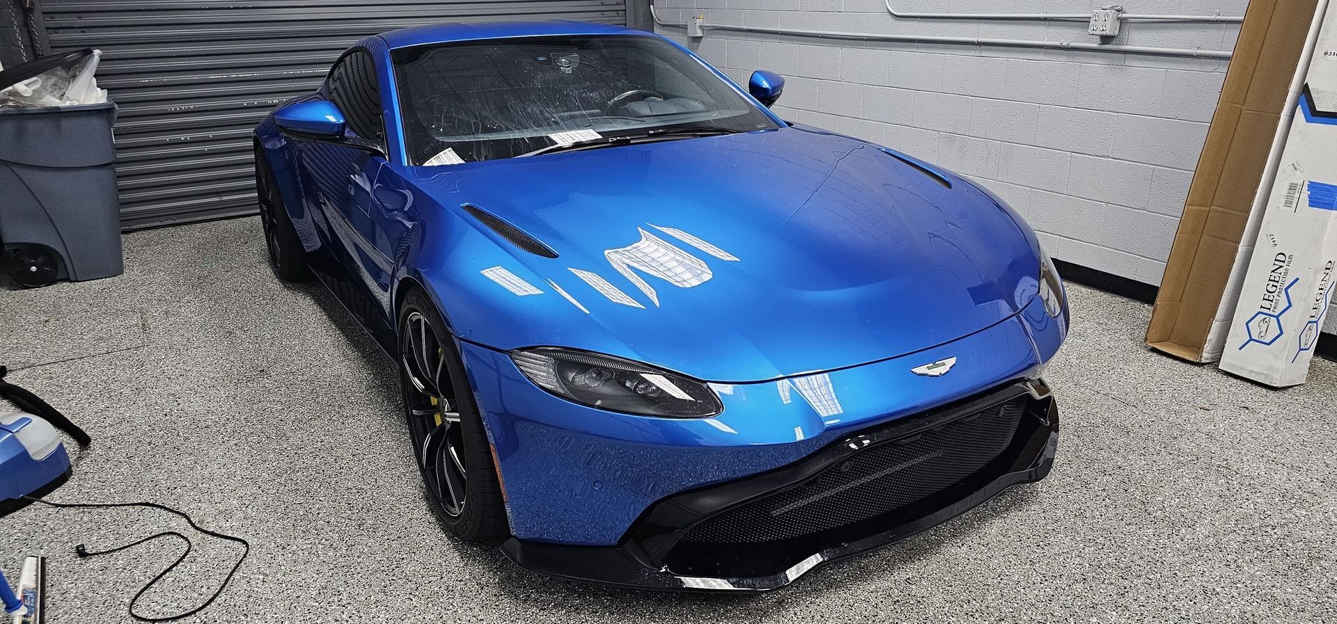 A person wearing black gloves is cleaning a car with a towel.