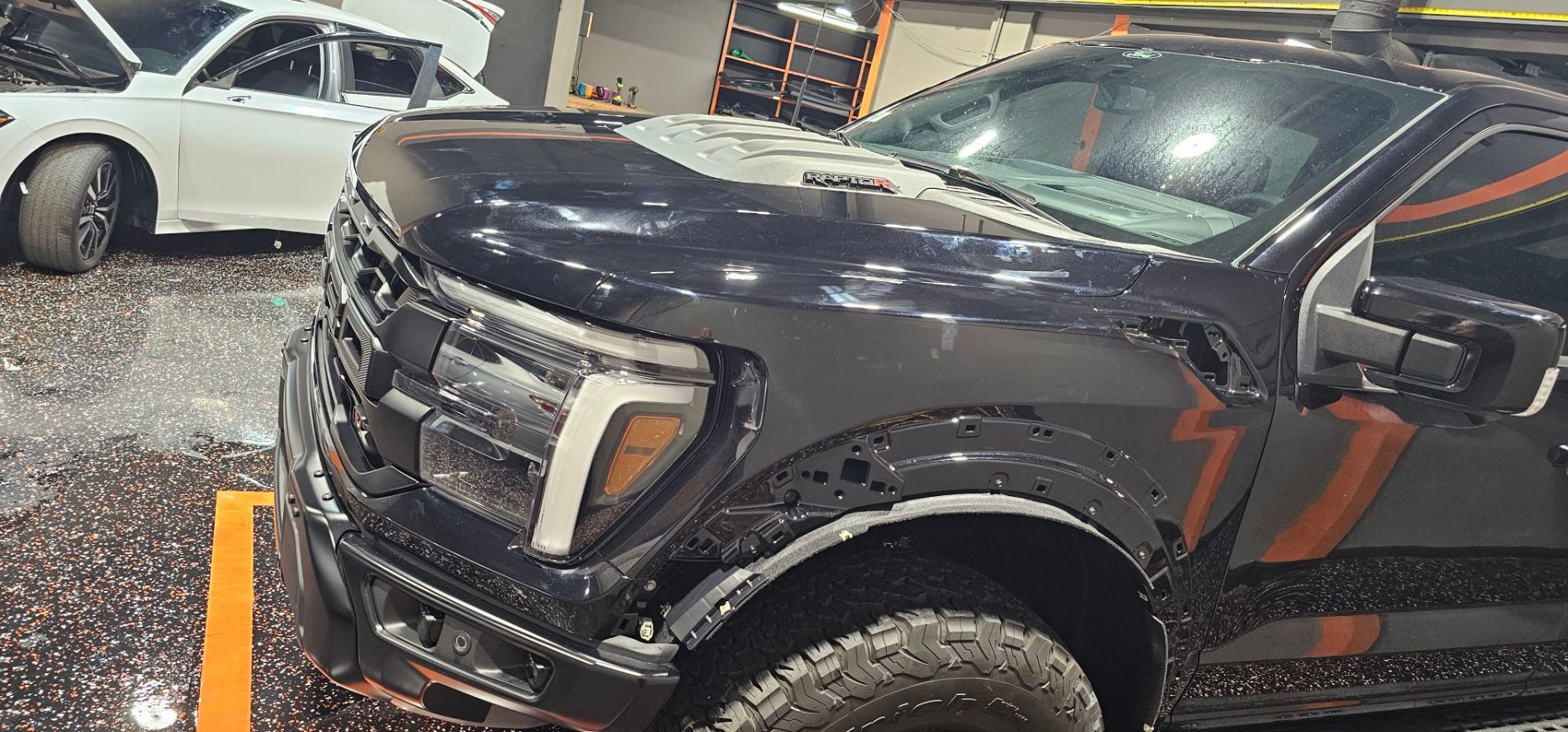 A black truck is parked in a parking lot next to a white car.