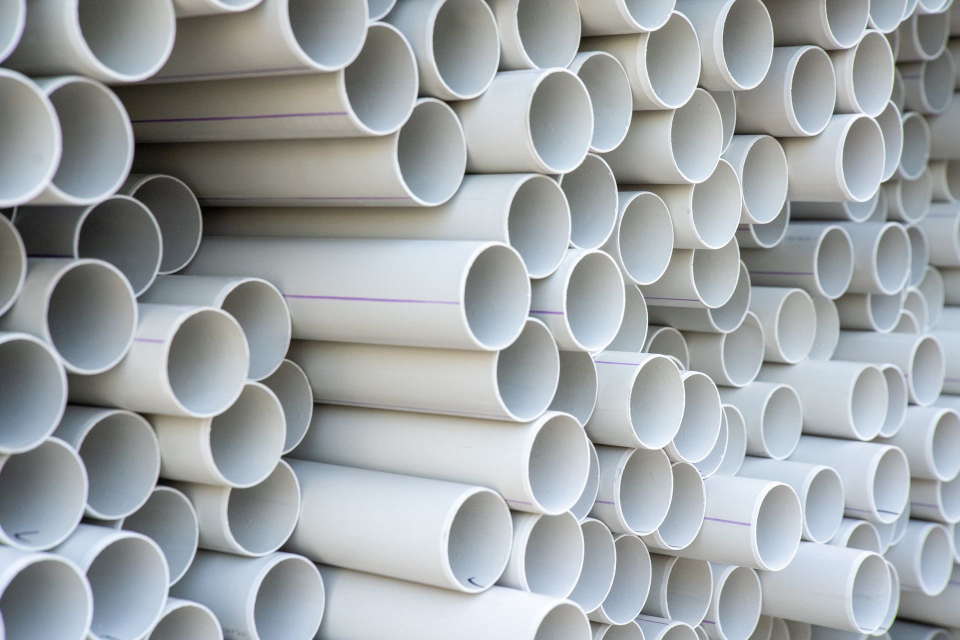 Stack of gray PVC pipes, showing open ends.