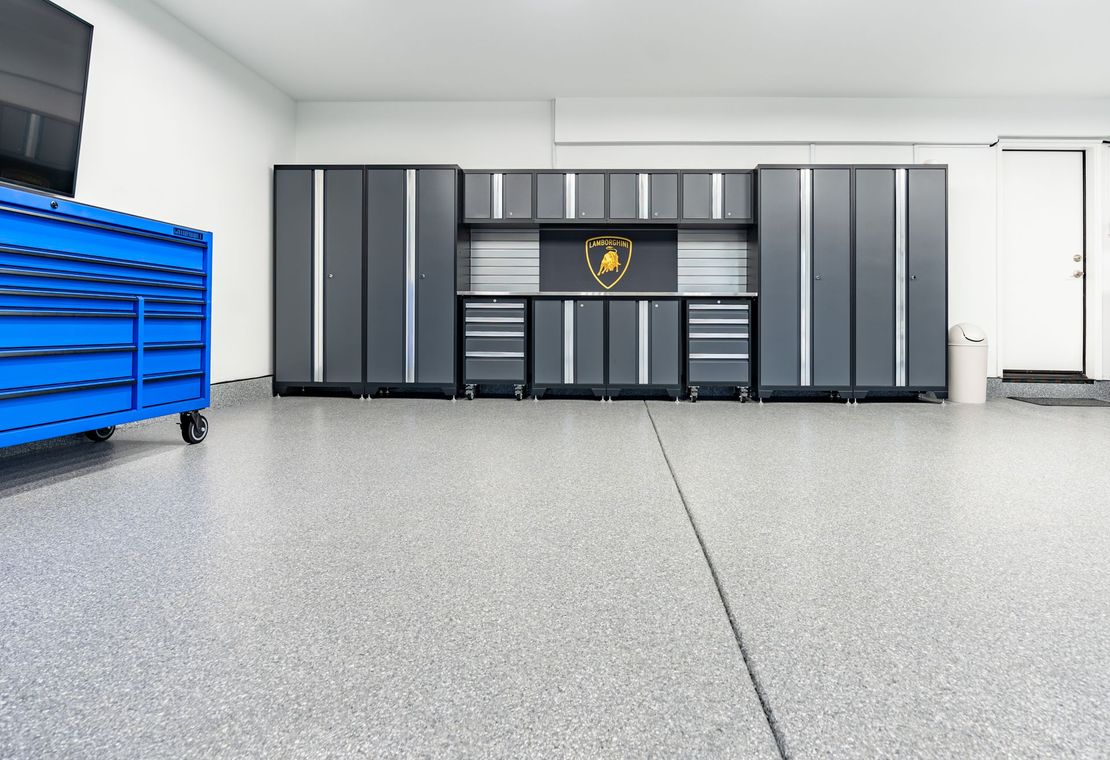 A garage with a lot of cabinets and a blue toolbox.