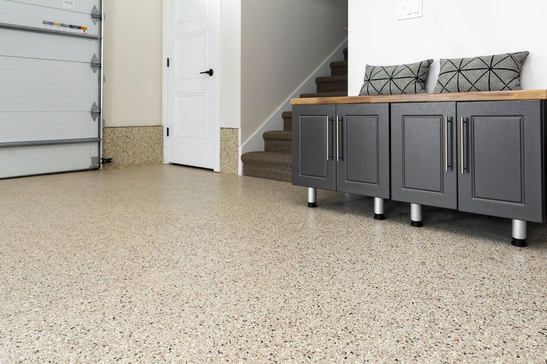 A garage with a concrete floor and cabinets and stairs.