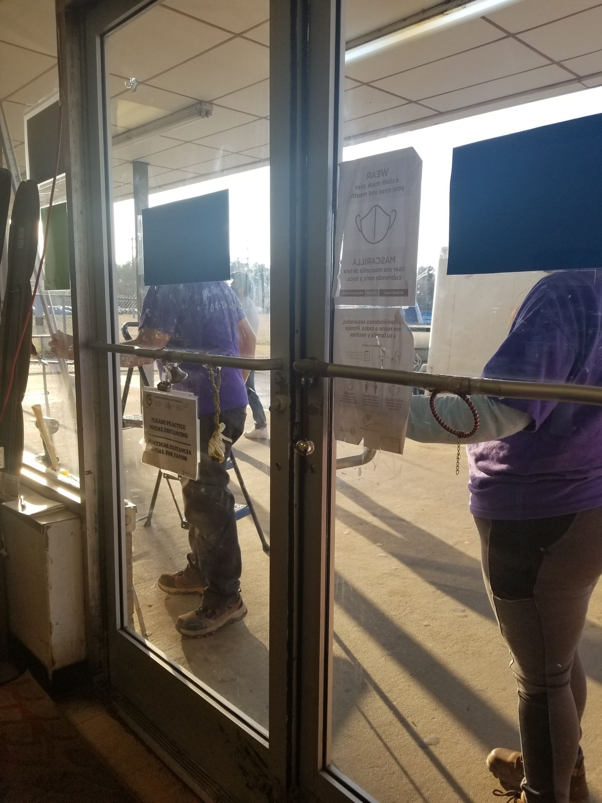 A woman in a purple shirt is standing in front of a glass door.